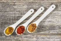 Tre cucchiai di spezie diverse sulla superficie di legno — Foto stock