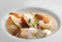 Vue rapprochée de la soupe aux crevettes avec des herbes dans un bol blanc — Photo de stock