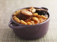 Bean stew in brown bowl over textile surface — Stock Photo