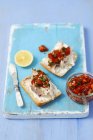 Ciabatta with smoked mackerel and tomato salsa on blue desk with knife — Stock Photo