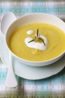Cream of courgette soup garnished with sour cream in white bowl over plate with spoon — Stock Photo