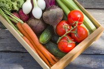 A wooden crate of fresh vegetables over wooden surface — Stock Photo
