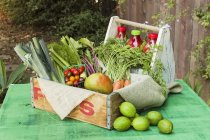 A wooden crate of fruit and vegetables on a rustic garden table — Stock Photo