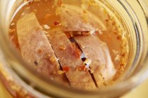 Closeup view of pickled and smoked sausage slices in a jar — Stock Photo