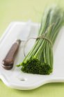 Bundle of fresh chives and knife — Stock Photo