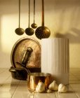 Kochmütze, Kupfertöpfe, Suppenkellen und Knoblauch — Stockfoto