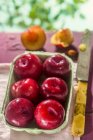 Prunes rouges dans un punnet en carton — Photo de stock