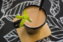 Крупним планом вид какао в чорній чашці з соломою і м'ятним гарніром — стокове фото