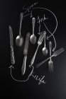 Vista dall'alto di vecchi coltelli, cucchiai e forchette su una superficie di ardesia con etichette — Foto stock