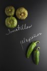 Tomatillos and jalapeos on a black slate surface with labels — Stock Photo