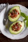 Gefüllte Avocado mit Tomatensalsa auf weißem Teller mit Löffel — Stockfoto