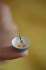 Vista close-up de uma tigela minúscula de ovos batidos em uma ponta do dedo — Fotografia de Stock