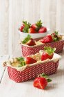 Vue rapprochée des fraises et gâteaux de quark dans des boîtes de cuisson à pois — Photo de stock