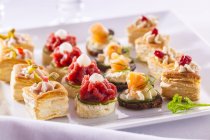 Closeup view of assorted party snacks in rows on white dish — Stock Photo