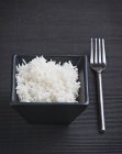 Варёный рис в чёрной тарелке — стоковое фото