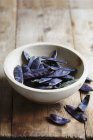 A bowl of purple mange tout over wooden surface — Stock Photo