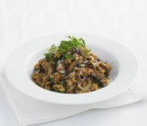 Closeup view of mushroom Risotto with rocket in white bowl — Stock Photo