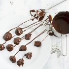 Chocolate-covered plums on plate — Stock Photo