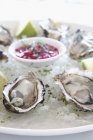Oysters on ice with lime slices — Stock Photo