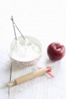 Closeup view of beaten egg whites with rolling pin and apple — Stock Photo