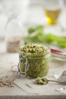 Primo piano vista di un barattolo aperto di pesto di basilico fresco circondato da ingredienti — Foto stock
