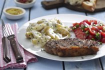 Rump steak with potato and tomato salads — Stock Photo