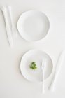 Vue de dessus des assiettes blanches, couverts et persil — Photo de stock