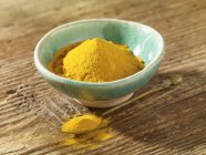 Turmeric powder in bowl and on spoon — Stock Photo