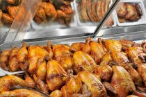 Closeup view of grilled chicken and other grilled meats in a fast food display — Stock Photo