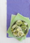 Anelli di porro congelati su tovaglioli di carta verde su superficie viola — Foto stock