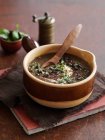 Черный бобовый суп в коричневой миске с деревянной ложкой — стоковое фото