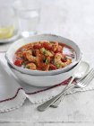 Tomaten-Garnelen-Suppe mit Petersilie auf weißem Teller über Handtuch mit Löffel und Gabel — Stockfoto