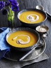 Cream of sweet potato soup in black dishes over black wooden surface — Stock Photo