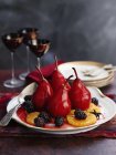 Closeup view of poached in red wine pears with blackberries and orange slices — Stock Photo