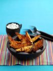 Fried sweet potato wedges with a dip in bowl over towel on blue background — Stock Photo