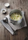 Pea risotto in a saucepan over textile towel  on wooden surface — Stock Photo
