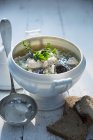 Цибульний суп з куркою в білому горщику на дерев'яній поверхні з соусом — стокове фото