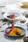 Turmeric powder, a dried chilli pepper, shiitake mushrooms and star anise on a table in front of a kitchen window — Stock Photo