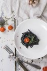 Black tagliolini pasta with baked tomatoes — Stock Photo