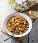 White bean soup with Italian salsiccia on white plate  over wooden surface — Stock Photo