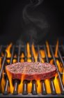Hamburger crudo su barbecue fiammeggiante — Foto stock