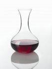 Visão de close-up de uma garrafa de bebida vermelha em uma superfície reflexiva branca — Fotografia de Stock