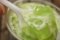 Closeup view of lime gelatina on spoon over glass — Stock Photo