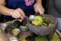 Guacamole in stone bowl over table with plates — Stock Photo