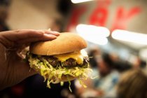 Weibliche Hand hält Hamburger — Stockfoto