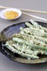 Green beans in tempura batter on black plate — Stock Photo