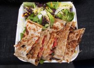 Elevated view of Mexican Quesadillas with vegetable salad on paper plate — Stock Photo