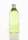 Closeup view of a bottle of grapeseed oil on a white surface — Stock Photo