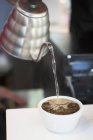 Крупним планом вид на воду до чашки кавових зерен — стокове фото