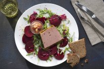 Goose liver terrine on beetroot  on white plate on table — Stock Photo